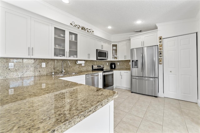 kitchen with stainless steel appliances, light stone countertops, white cabinets, and sink