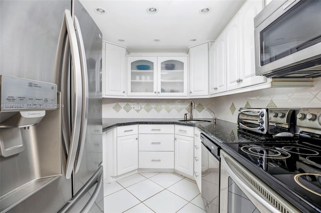 kitchen featuring backsplash, appliances with stainless steel finishes, white cabinets, and dark stone countertops