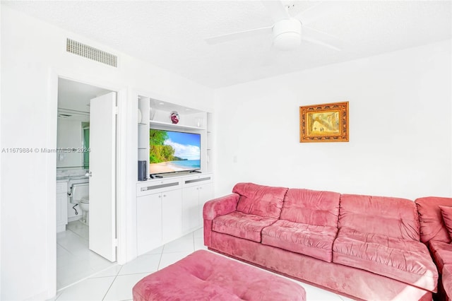 living room with ceiling fan, a textured ceiling, and light tile patterned floors