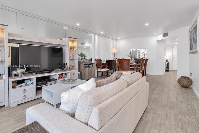 living room with baseboards, visible vents, wood finish floors, and recessed lighting