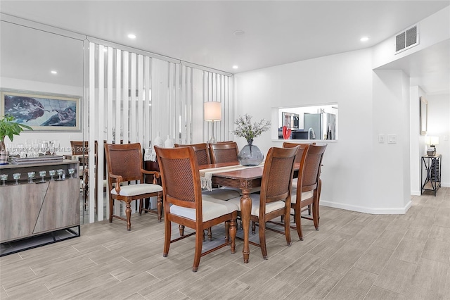 dining space featuring wood tiled floor, visible vents, baseboards, and recessed lighting