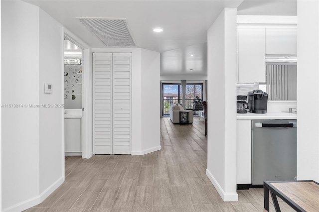 hall with recessed lighting, visible vents, light wood-style flooring, and baseboards