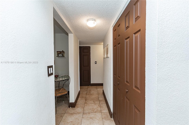 corridor featuring light tile patterned floors and a textured ceiling