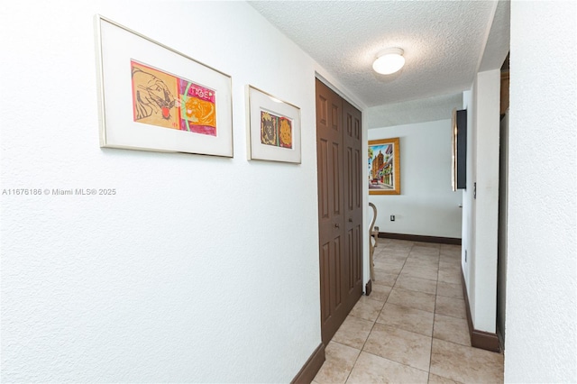 hallway with light tile patterned floors and a textured ceiling