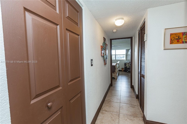 hallway featuring light tile patterned floors and a textured ceiling