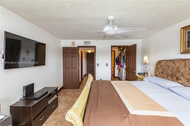 bedroom with ceiling fan, a walk in closet, a textured ceiling, and a closet
