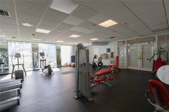 workout area with a drop ceiling, expansive windows, and french doors