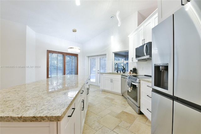 kitchen with french doors, stainless steel appliances, a center island, pendant lighting, and white cabinetry