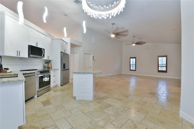 kitchen with tasteful backsplash, light stone countertops, hanging light fixtures, white cabinetry, and stainless steel appliances