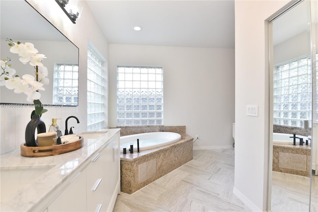 bathroom with vanity and tiled bath