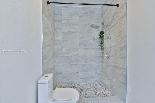 bathroom with a tile shower and toilet