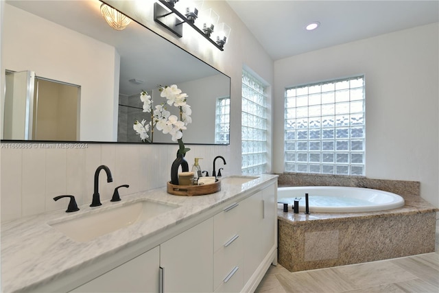 bathroom featuring vanity, a relaxing tiled tub, and tile patterned floors