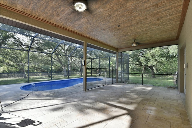 view of swimming pool featuring a patio, ceiling fan, and glass enclosure