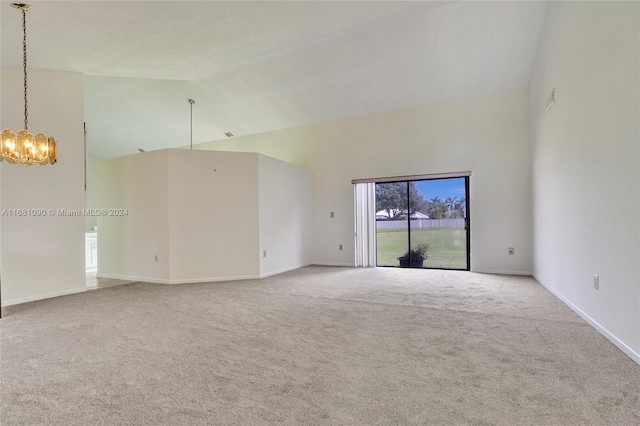 carpeted spare room featuring a notable chandelier and high vaulted ceiling