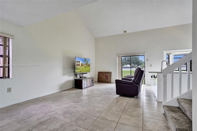 living room featuring high vaulted ceiling, a textured ceiling, and light tile patterned floors