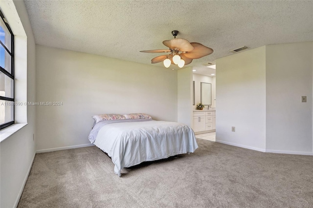 bedroom featuring ceiling fan, light carpet, a textured ceiling, and ensuite bathroom