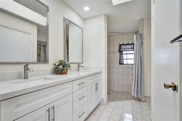 bathroom featuring tile patterned floors, walk in shower, vanity, a textured ceiling, and a skylight