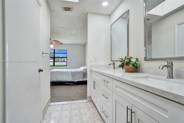 bathroom with vanity, a textured ceiling, and a skylight