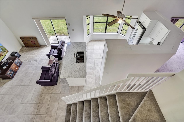 living room with a towering ceiling, light tile patterned flooring, and ceiling fan