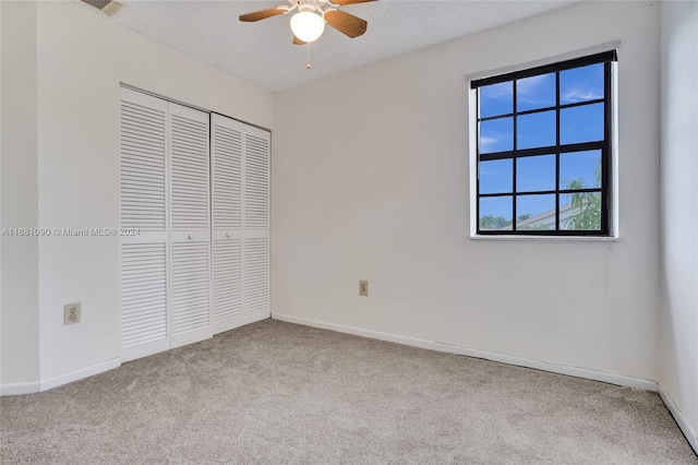 unfurnished bedroom with light carpet, a closet, a textured ceiling, and ceiling fan