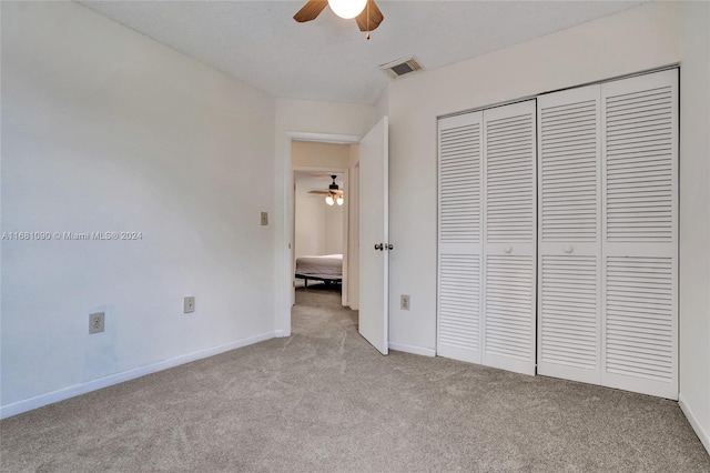 unfurnished bedroom with a closet, light colored carpet, and ceiling fan