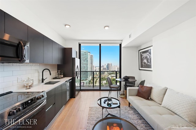 kitchen with stainless steel appliances, sink, tasteful backsplash, light wood-type flooring, and floor to ceiling windows