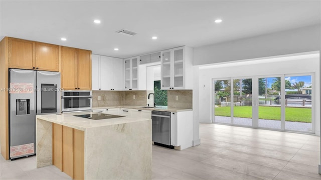 kitchen with white cabinetry, sink, decorative backsplash, a center island, and stainless steel appliances