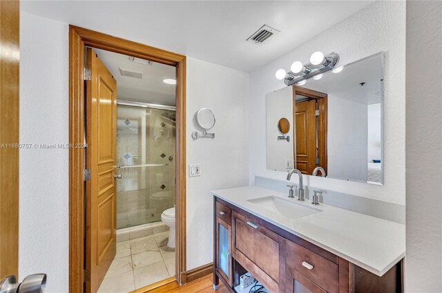 bathroom featuring a shower with door, vanity, and toilet