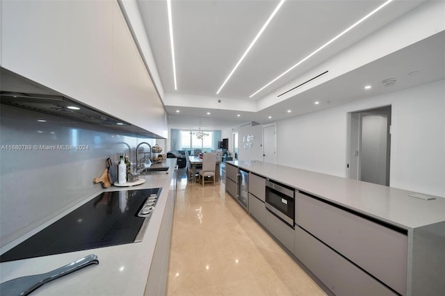 kitchen featuring sink, white cabinets, stainless steel microwave, and black electric cooktop