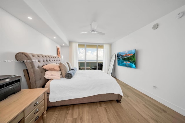 bedroom featuring light hardwood / wood-style floors, a wall of windows, and ceiling fan