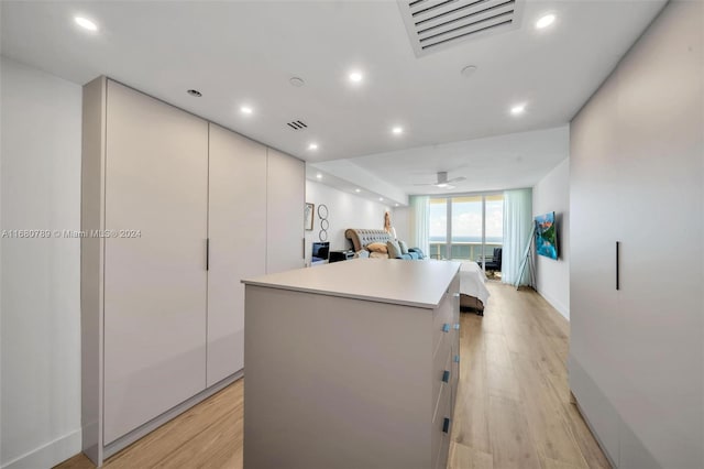 kitchen with white cabinetry, a center island, and light wood-type flooring