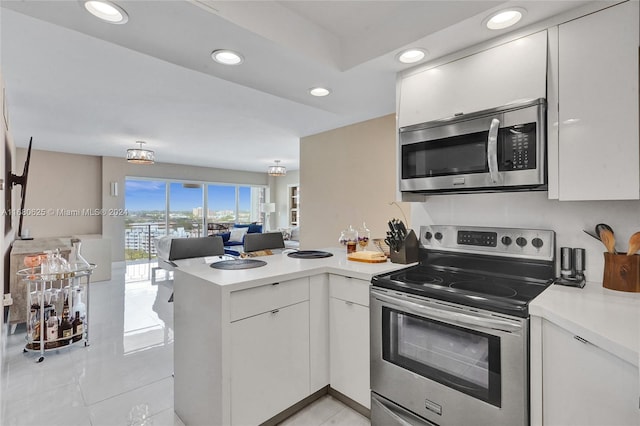 kitchen featuring appliances with stainless steel finishes, kitchen peninsula, white cabinets, decorative backsplash, and light tile patterned floors