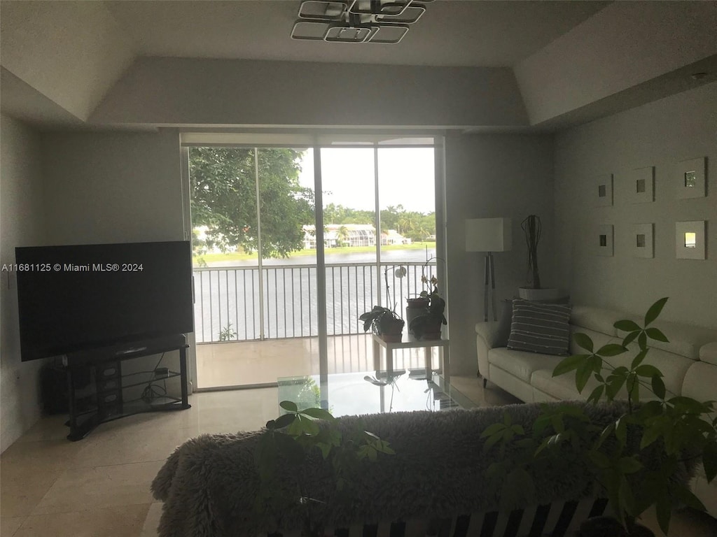 tiled living room with a water view and vaulted ceiling