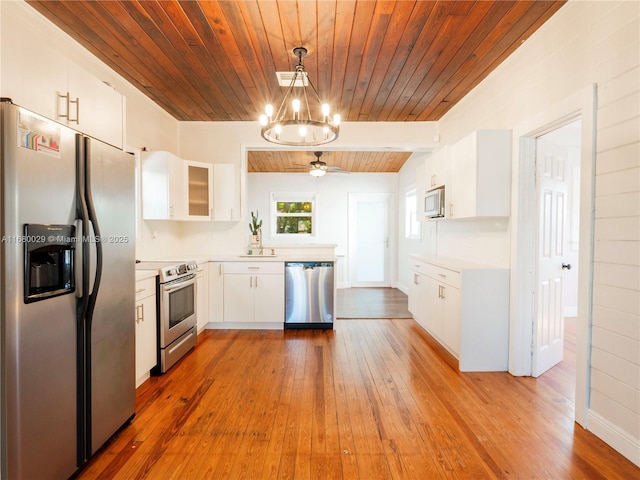 kitchen with white cabinetry, hardwood / wood-style floors, stainless steel appliances, decorative light fixtures, and wooden ceiling