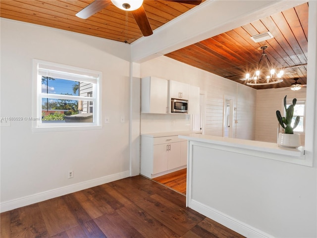 kitchen with stainless steel microwave, dark wood-style floors, ceiling fan with notable chandelier, and white cabinets