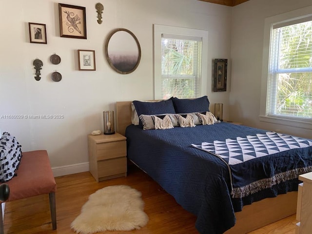 bedroom with baseboards, radiator heating unit, and light wood-style floors