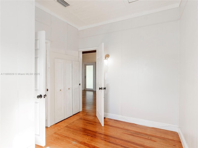 empty room featuring visible vents, light wood-type flooring, and baseboards