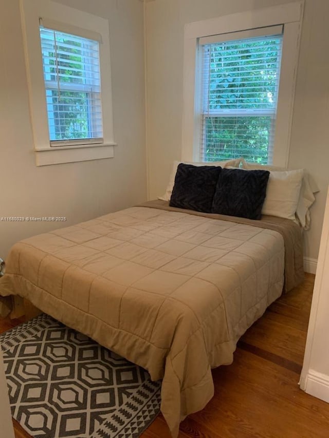 bedroom featuring multiple windows, wood finished floors, and baseboards