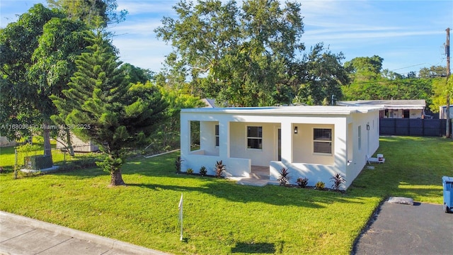 view of front of house featuring a porch, fence, a front lawn, and stucco siding