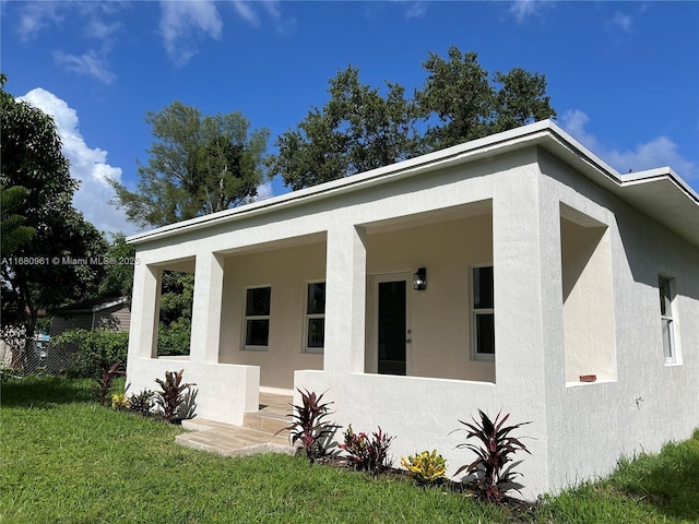 view of front of house featuring stucco siding and a front lawn