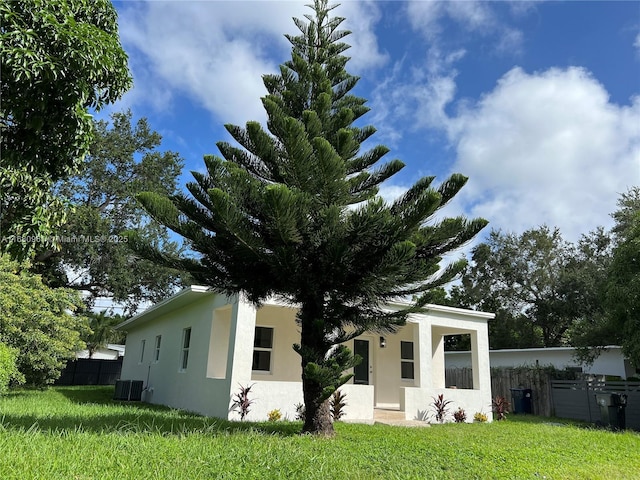 view of front of property with a front yard and central AC unit