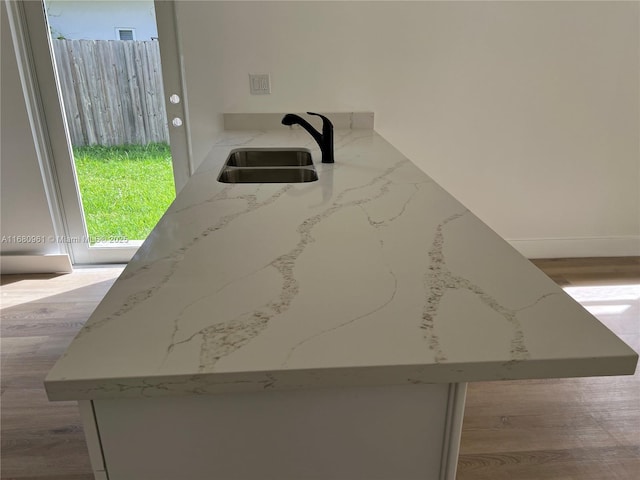 interior details with light stone counters, wood finished floors, and a sink