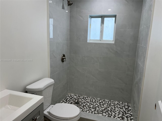full bathroom featuring tiled shower, toilet, and vanity