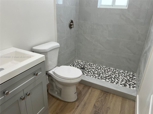 bathroom featuring a tile shower, vanity, toilet, and hardwood / wood-style floors