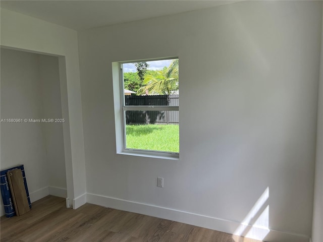 unfurnished room with baseboards, plenty of natural light, and wood finished floors