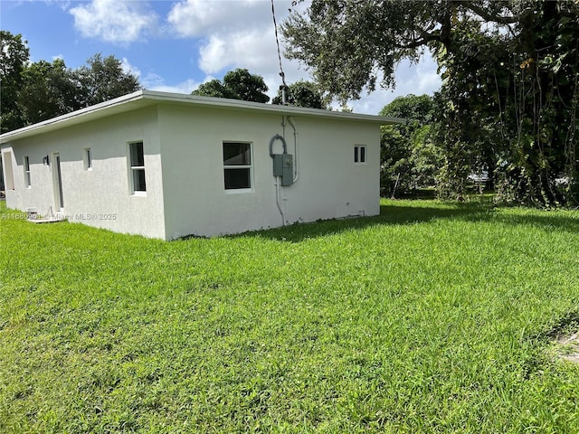 view of side of property with stucco siding and a lawn