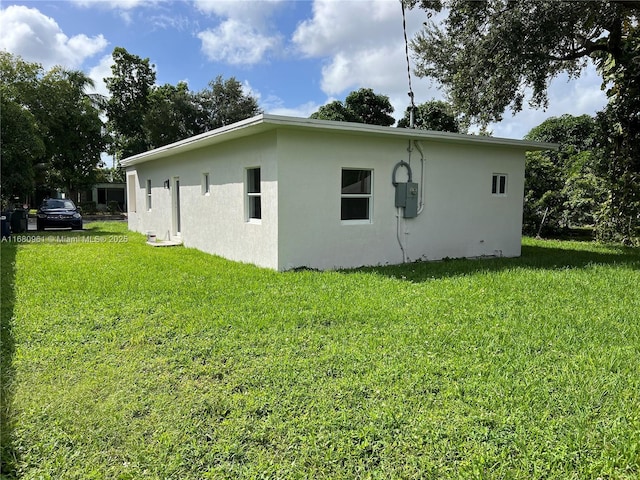 view of property exterior with stucco siding and a yard