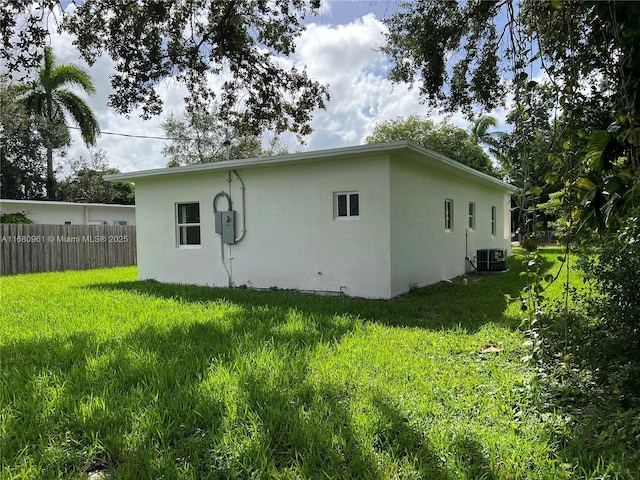 back of house featuring a yard, stucco siding, central AC, and fence