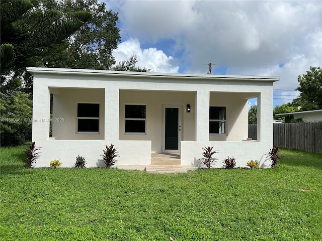 view of front facade with stucco siding, covered porch, a front yard, and fence