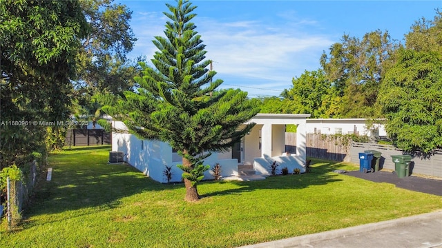 view of side of property with fence, a lawn, and stucco siding